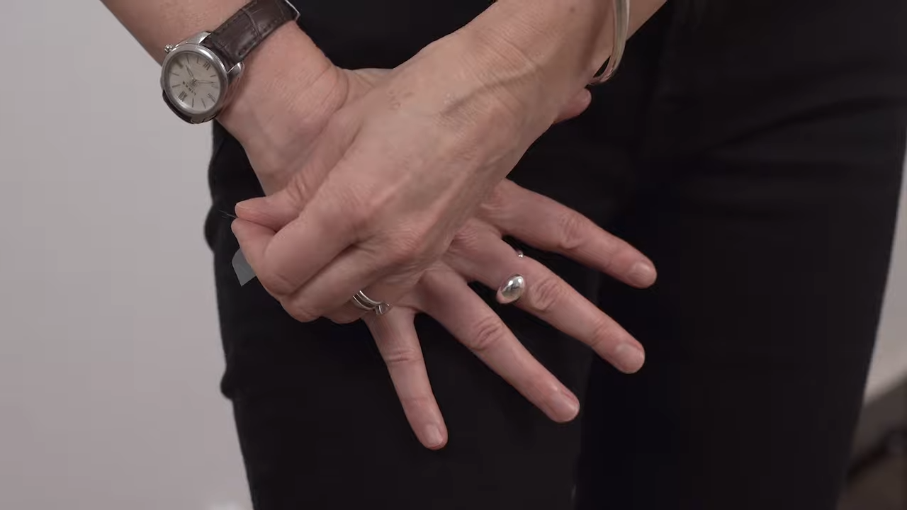 A woman's hands pressing a hormone patch onto her thigh.