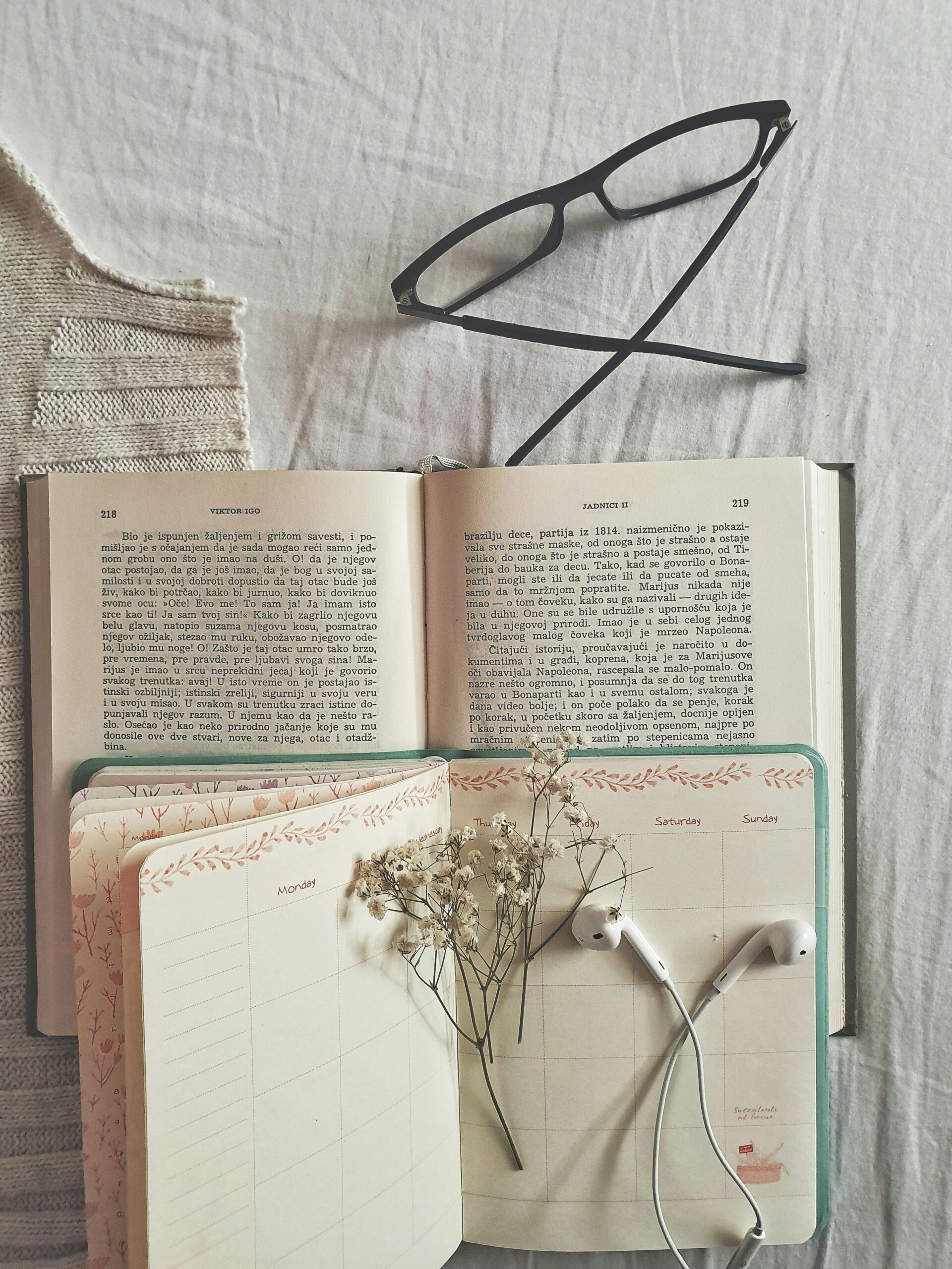 A photo of a paper diary with days of the week written in the header and dried flowers on the pages.